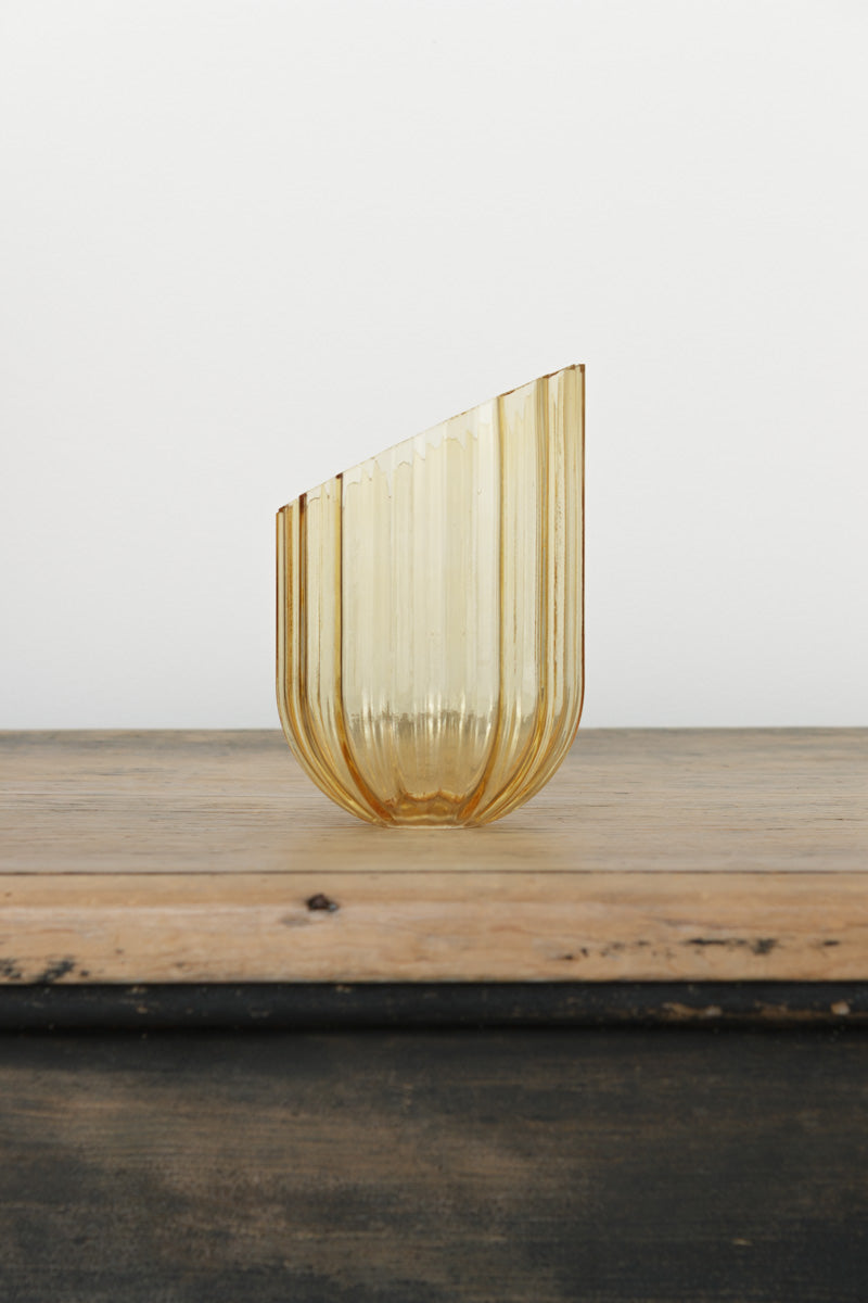 An amber glass shade with an elongated design, it has fluted detailing and features an angled cut edge. 