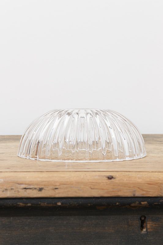 Clear Deloraine pressed glass shade with broad tapered ridges resting on a rustic timber surface.