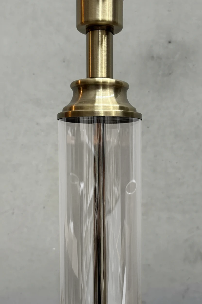 Close up of the ntique brass lamp stand detailing with the clear glass cylinder. 