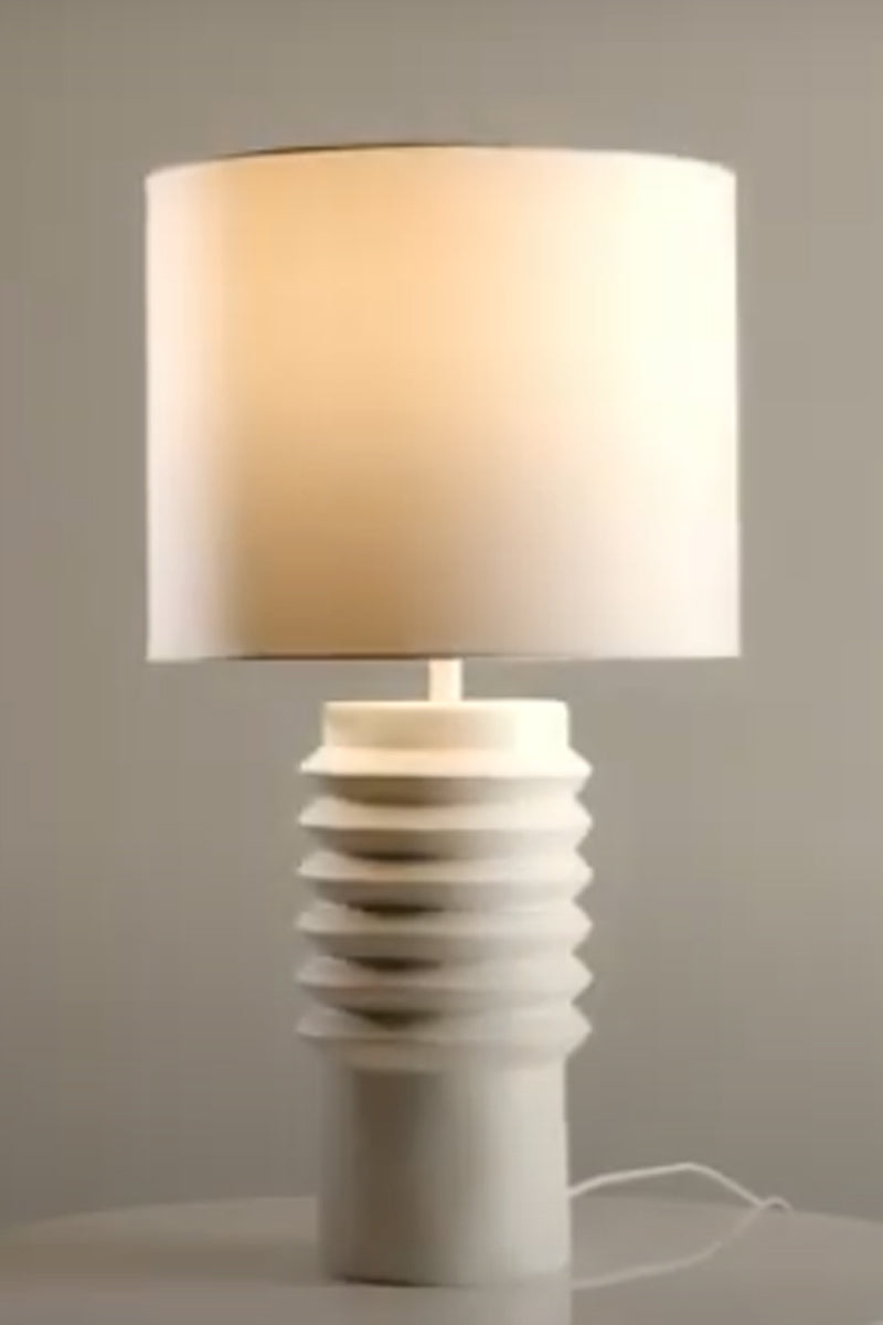 White ceramic based shade with a white linen fabric shade and warm kelvin bulb. 