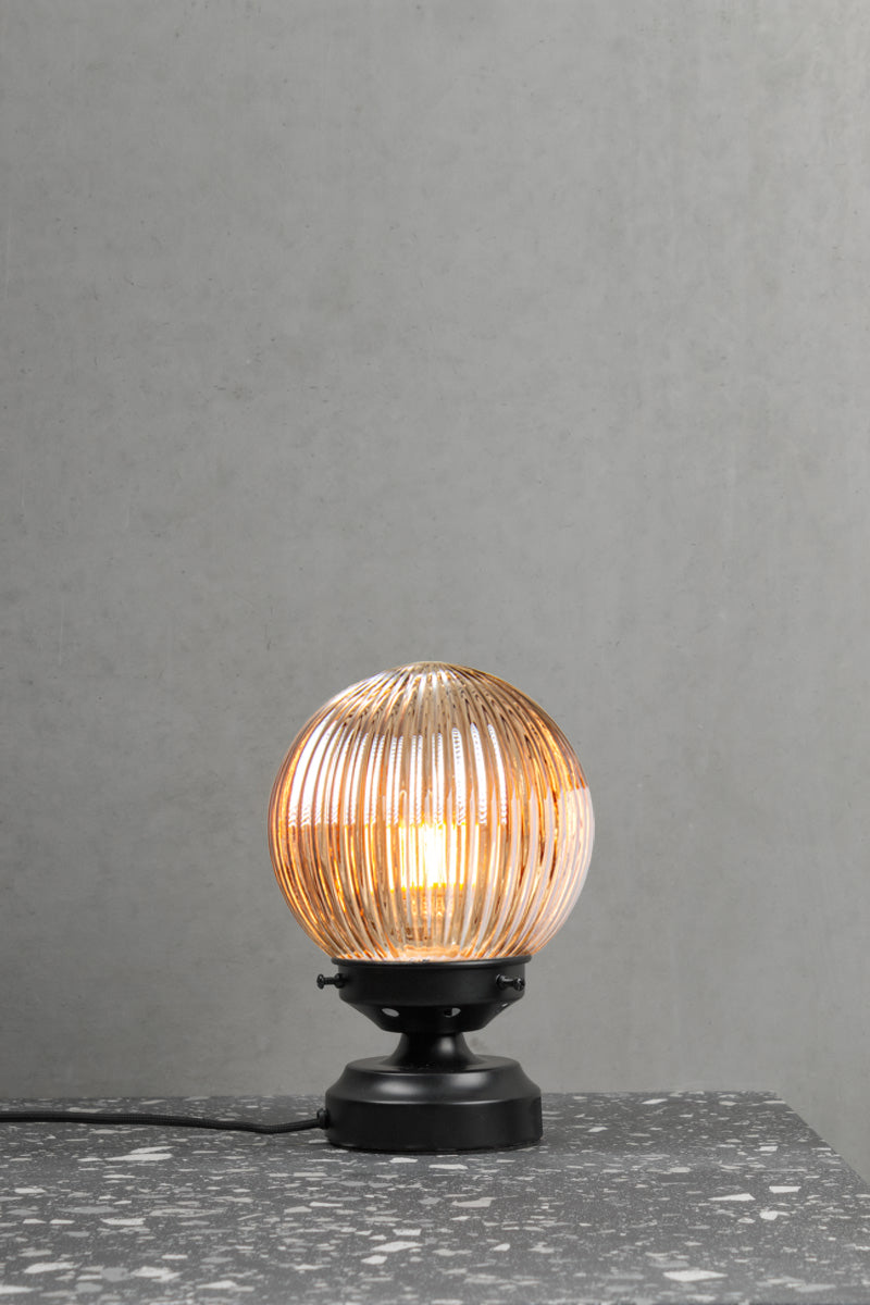 Dark amber reeded glass ball lamp with a black base. 