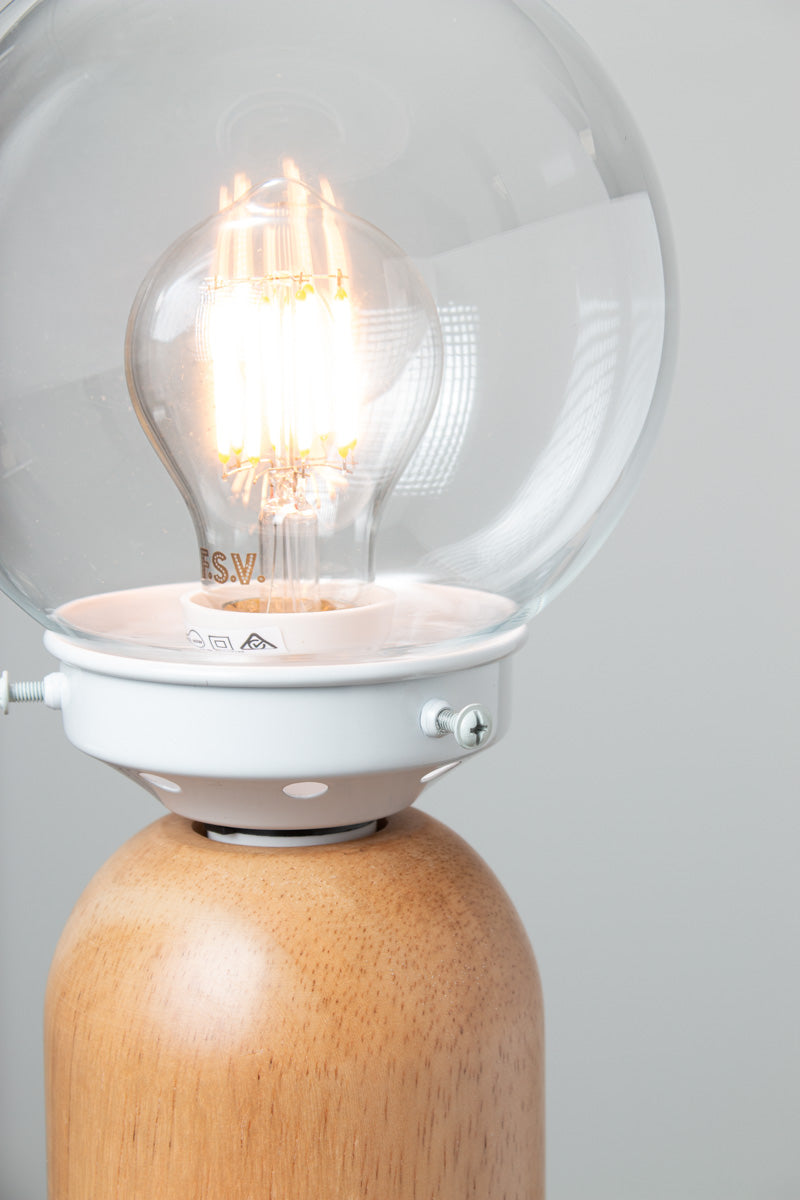Close up of the clear glass ball shade, white gallery paired with a wood table lamp base. 