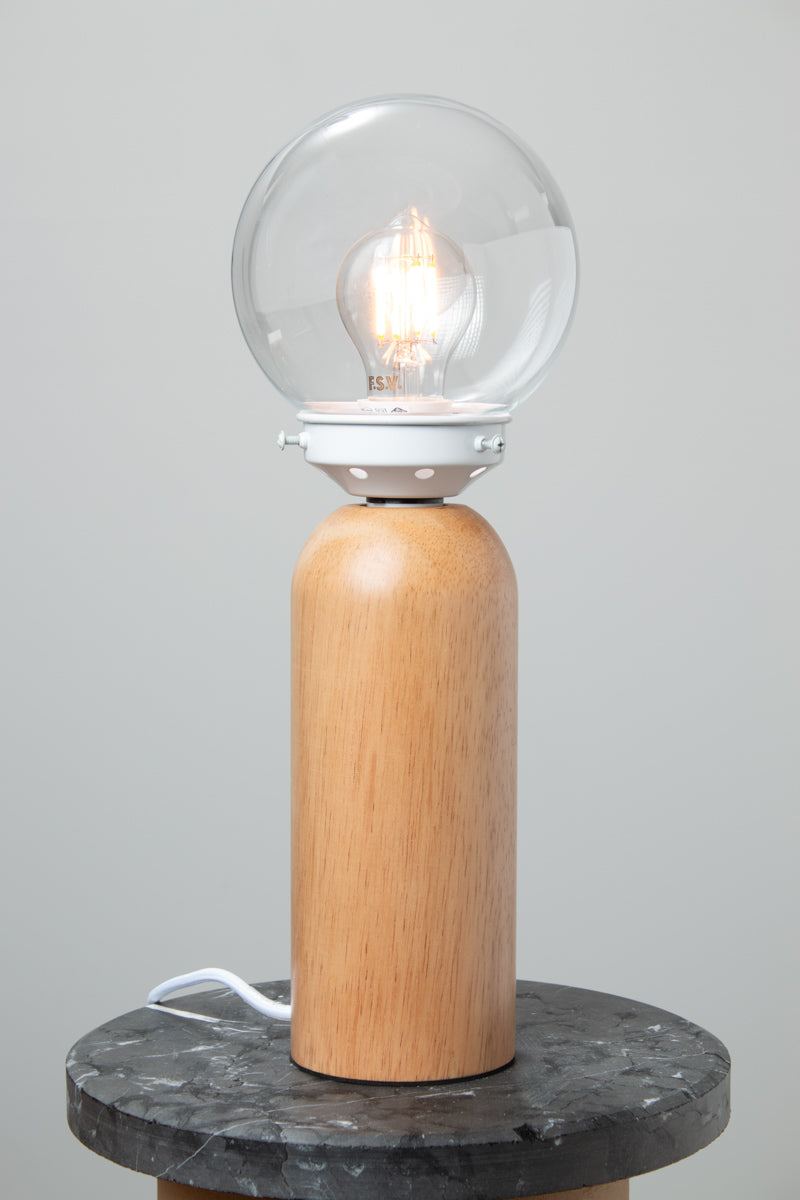 Clear glass ball shade, white gallery paired with a wood table lamp base on a marble look ride able. 
