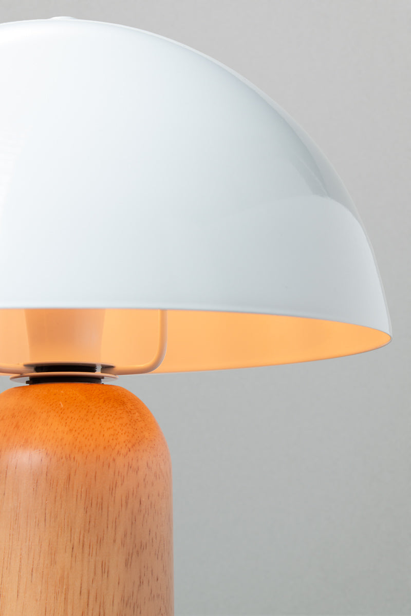 Close up of the table lamp with a white metal dome shade and rounded wood base with a natural finish.