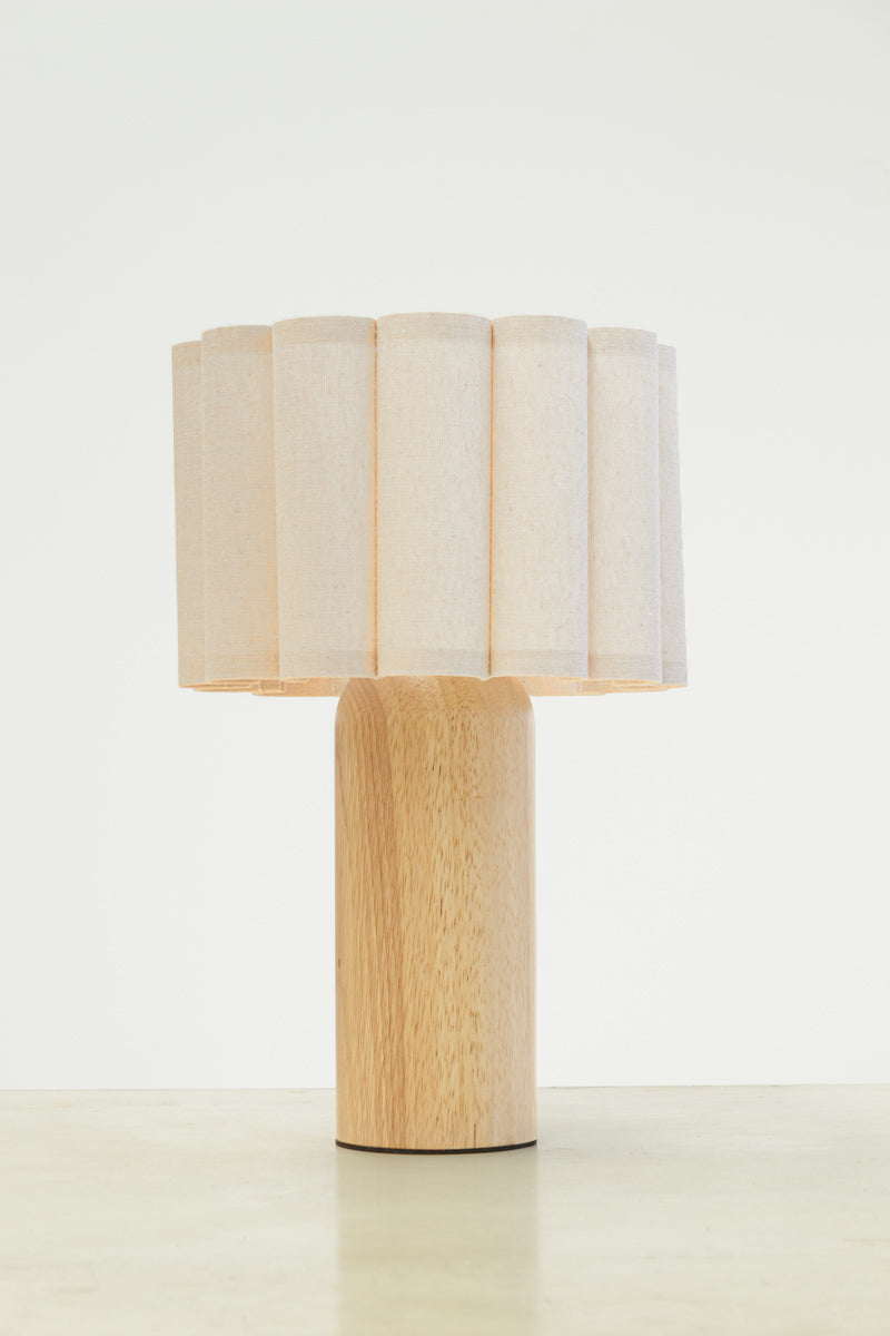 Natural fabric shade with scalloped detailing paired with a curved wood block table lamp base. 