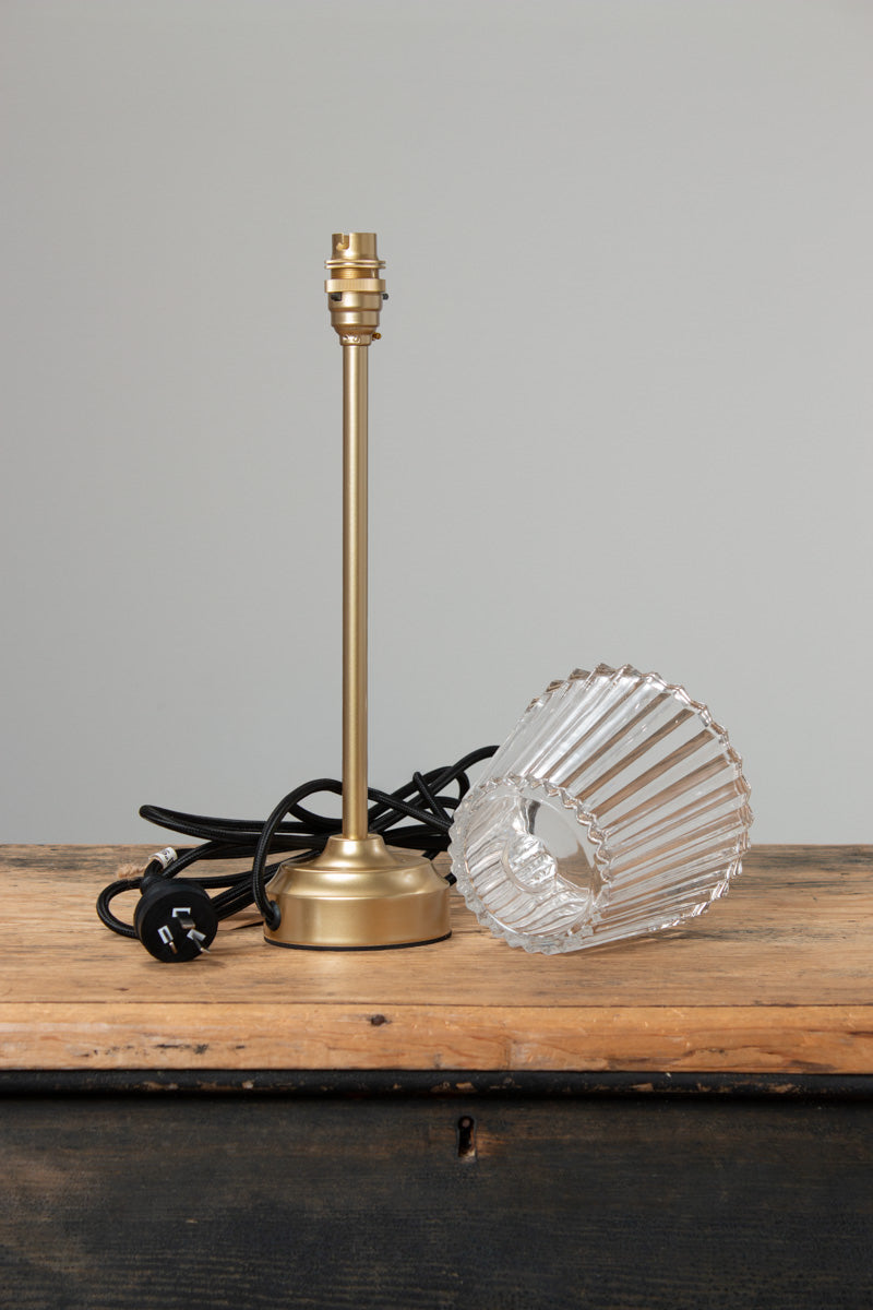 Separate pieces of the Davis Glass Candlestick Table Lamp in Gold/Brass on a timber bench.  