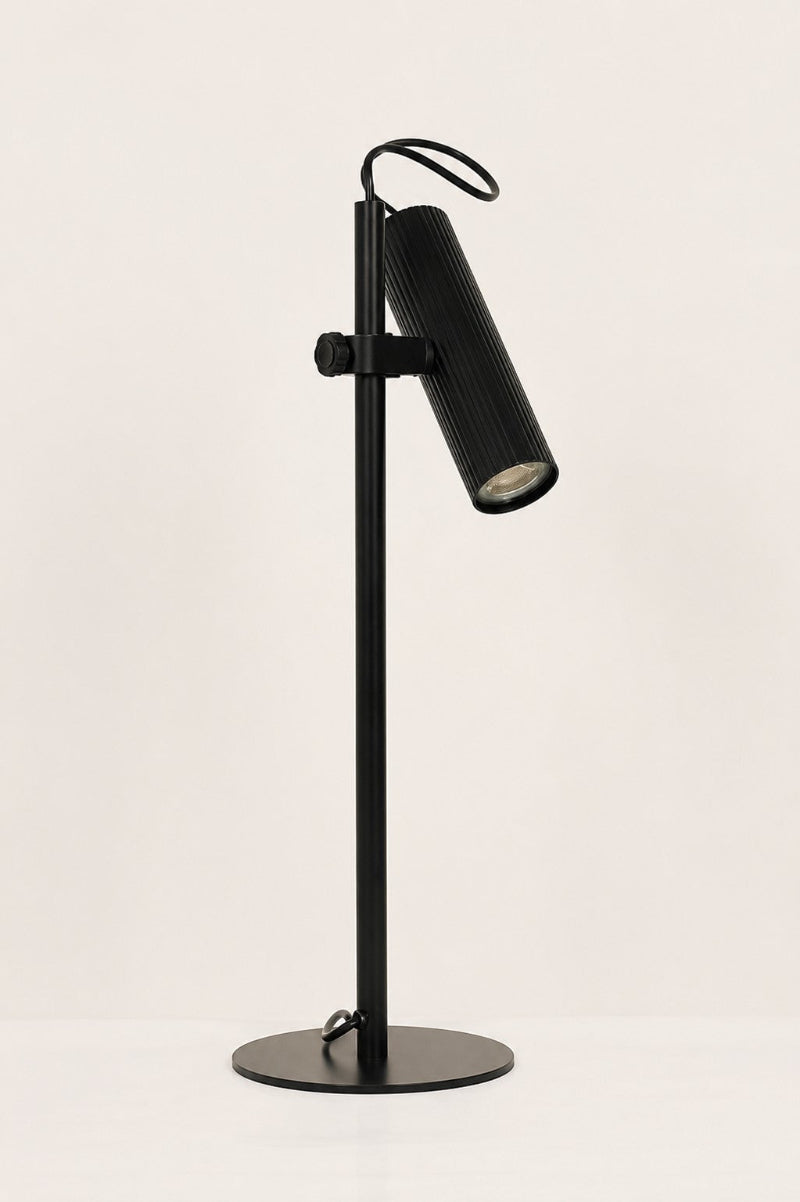 Black Collie desk lamp with the light off in a white space. 
