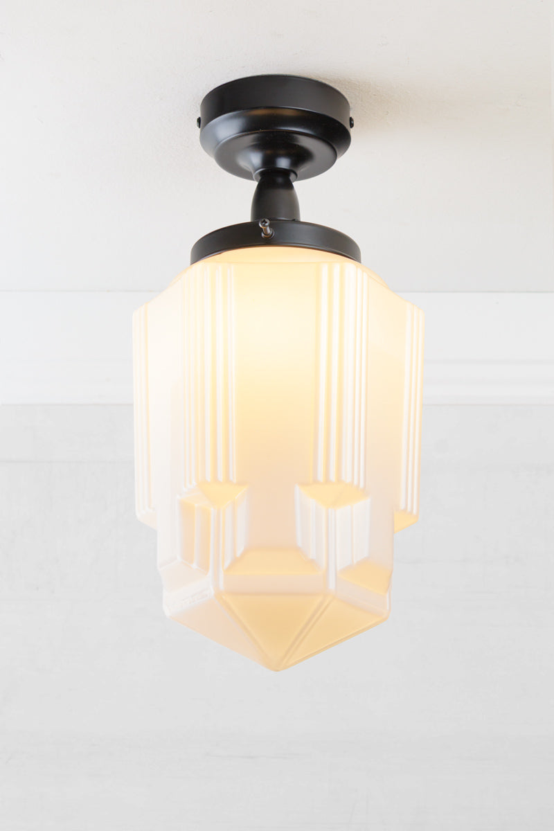 Geometric opal glass shade with art deco influence, paired with a black batten holder and gallery. 
