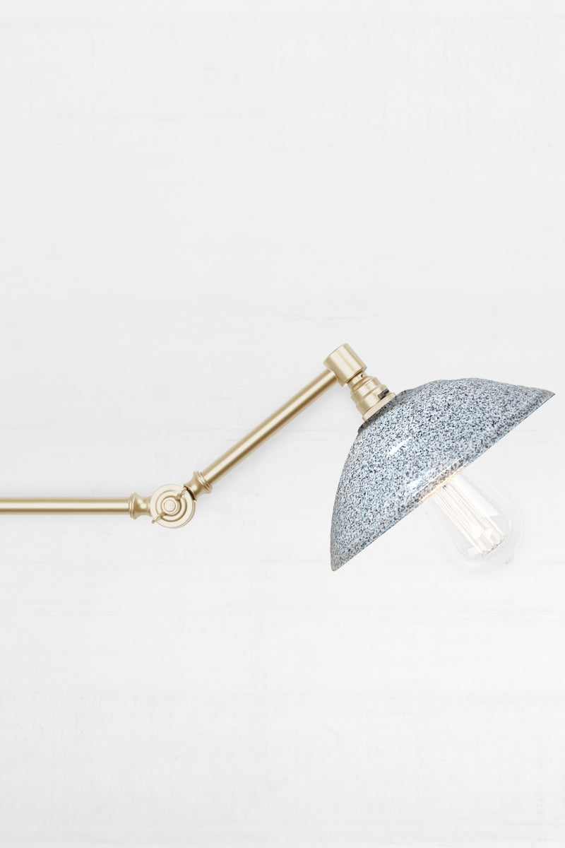 Close up of the Swing Arm Wall Lamp in gold arm finish with white/black Bakelite shade 