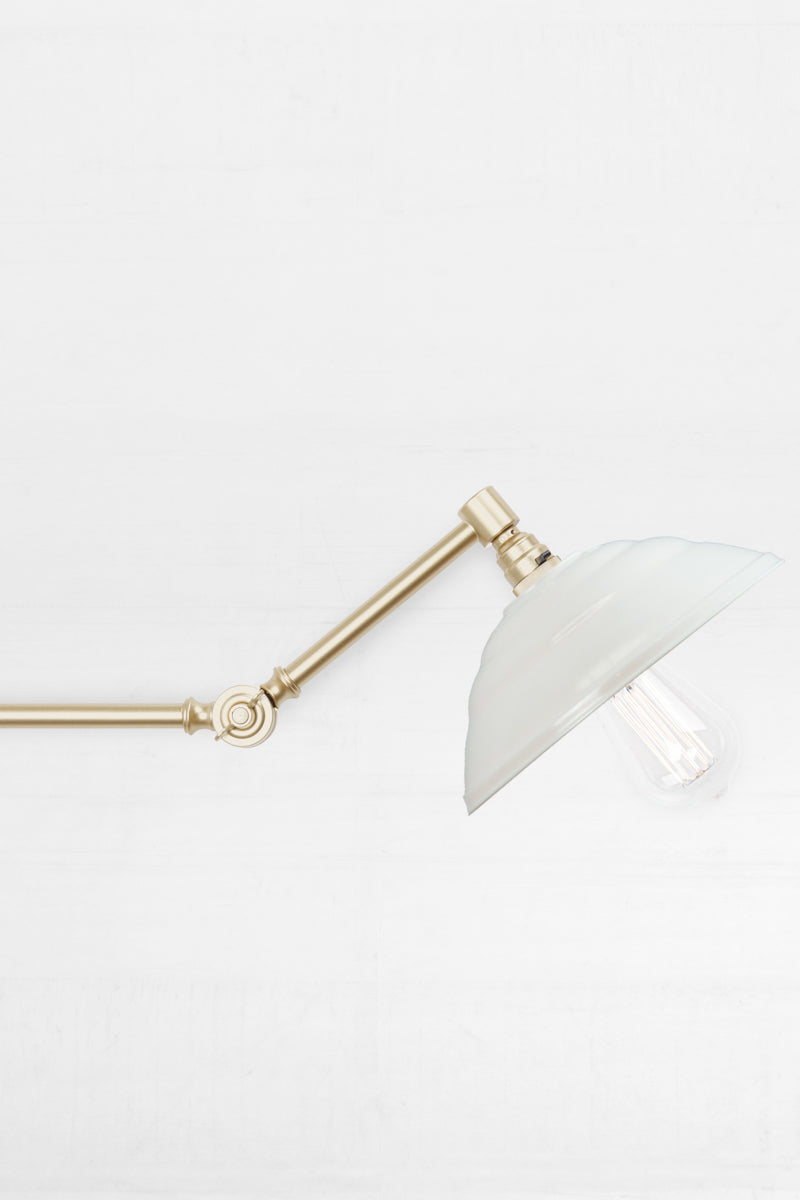 Close up of the Swing Arm Wall Lamp in gold arm finish with white Bakelite shade 