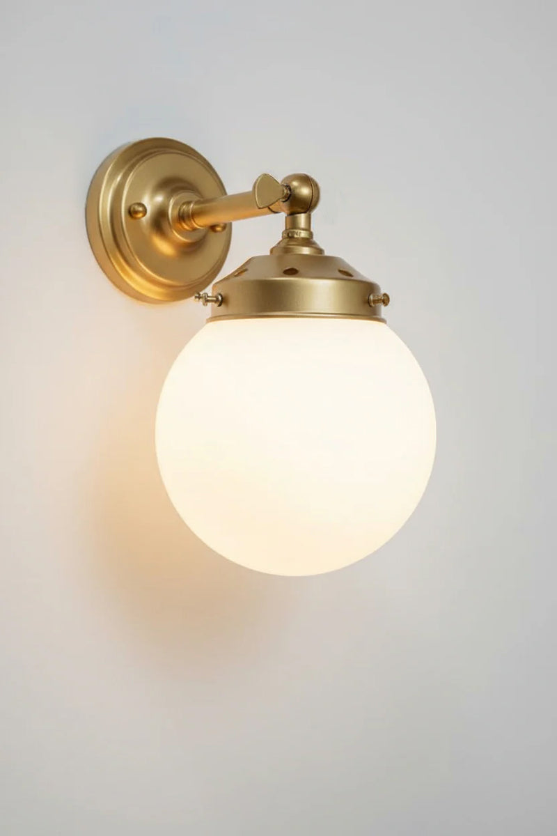 Small opal glass ball shade on a short gold/brss wall sconce