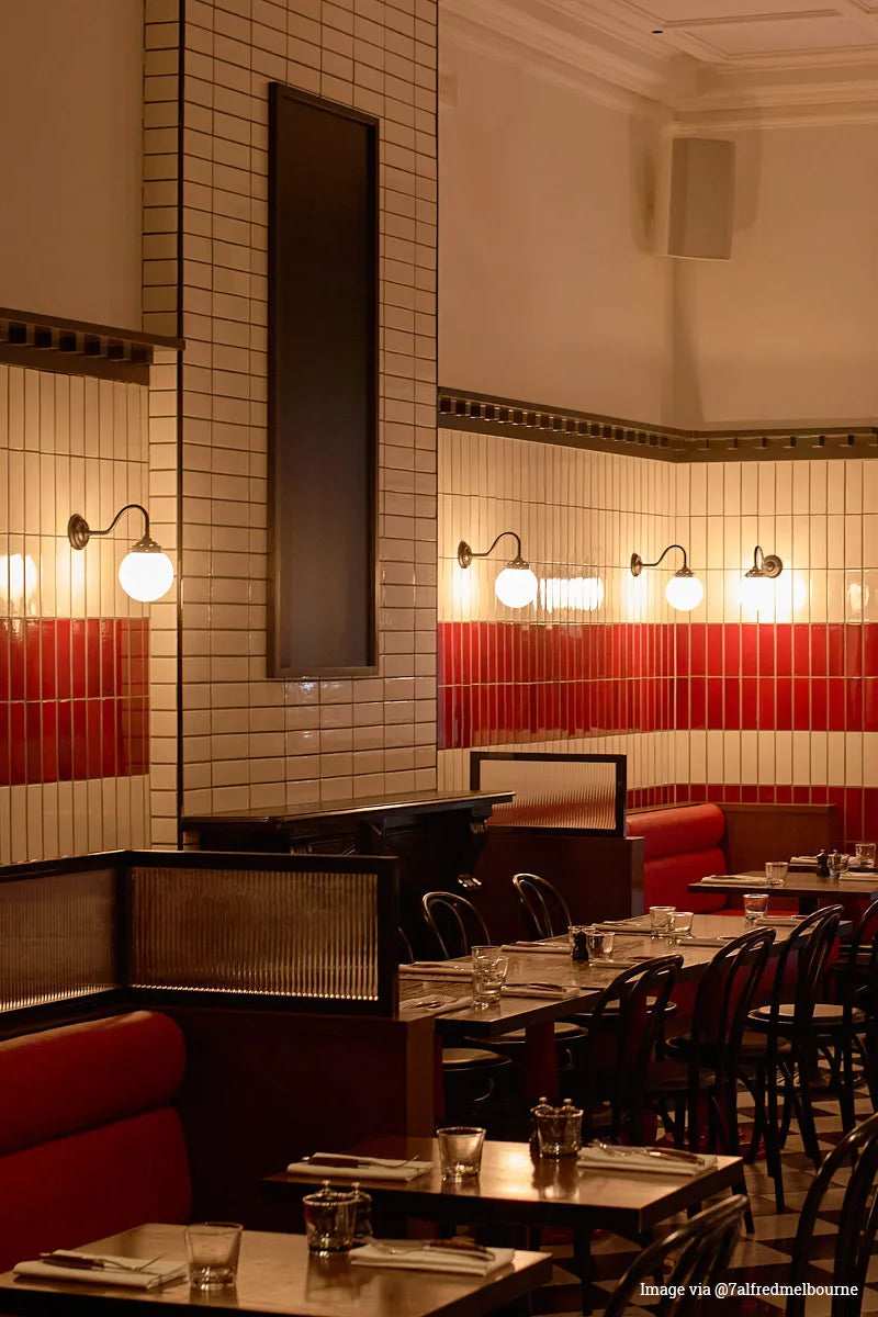 Image via @7alfredmelbourne: Four opal glass ball shades on black brass gooseneck wall sconces in a vintage inspired Melbourne restaurant.