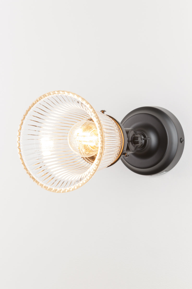 Fully extended adjustable wall batten in black with a small clear glass shade with ribbed detailing.