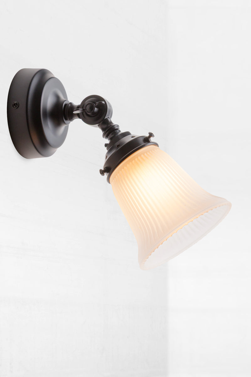 Slightly extended adjustable wall batten in black with a small opal glass shade with ribbed detailing.