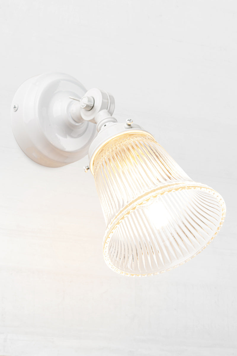Slightly extended adjustable wall batten in white with a small clear glass shade with ribbed detailing.