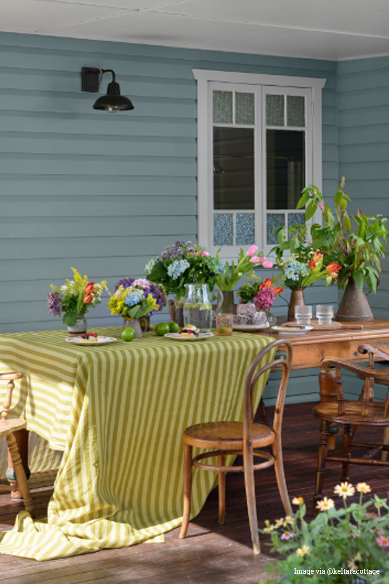 Railway wall light on a bllue watherboard house with a brightly decorated dining table. 