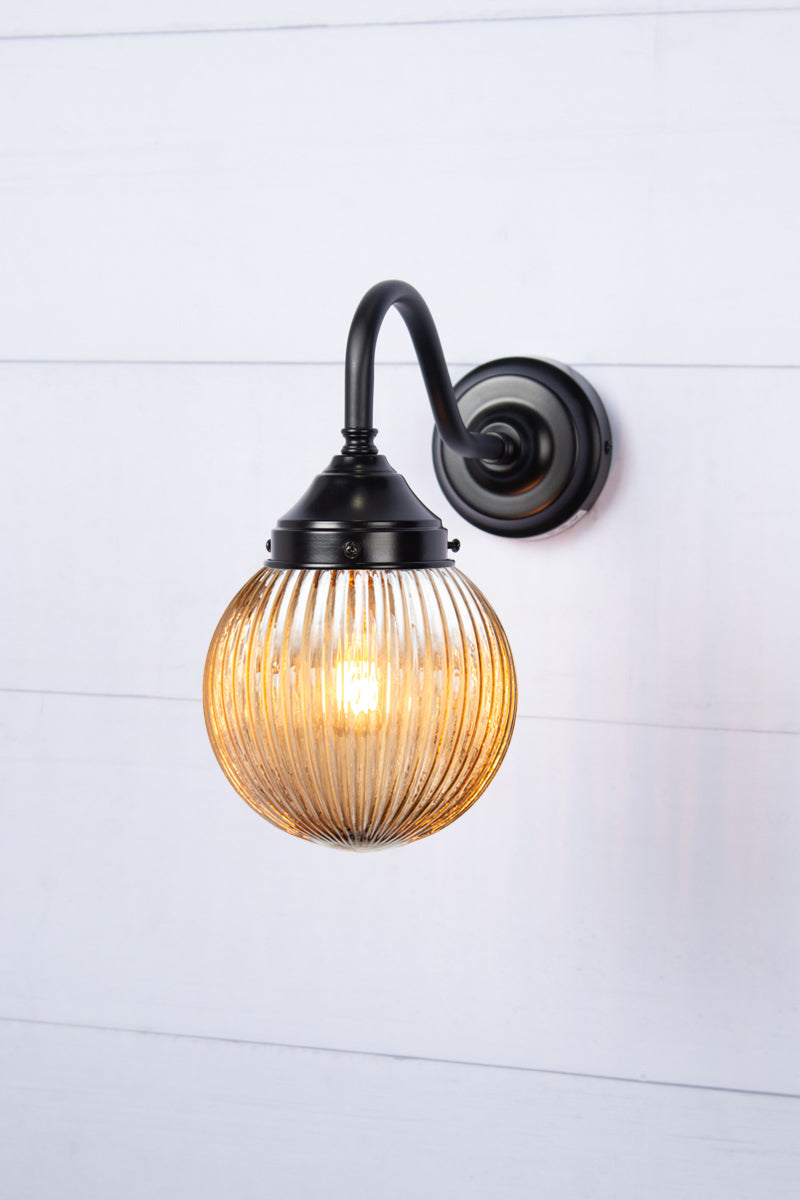 Exterior wall light with a black gooseneck arm and dark amber reeded shade.