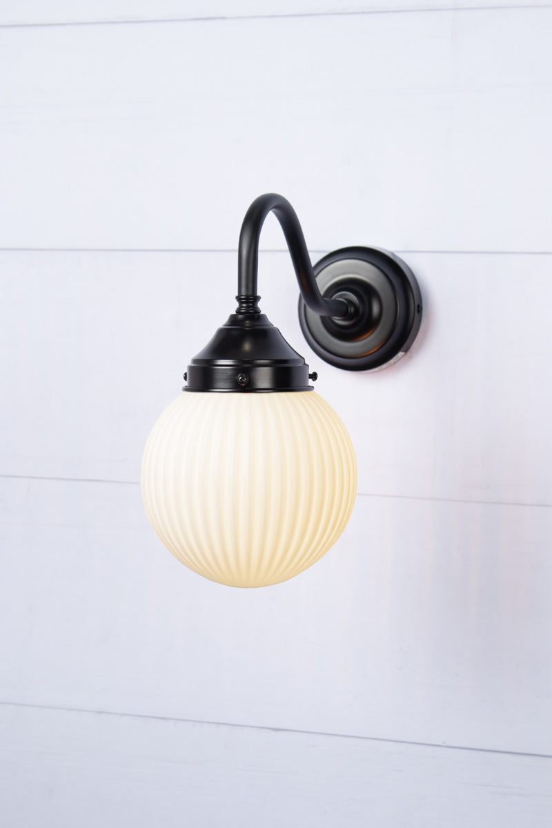 Exterior gooseneck wall arm in black with an opal glass ball shade with reeded detailing.