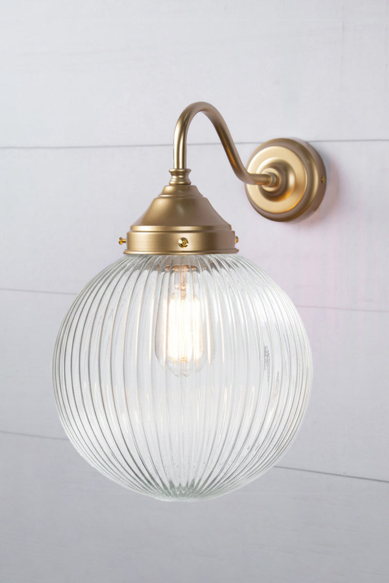 Exterior wall light with a gold/brass gooseneck arm and medium clear reeded shade, side view.