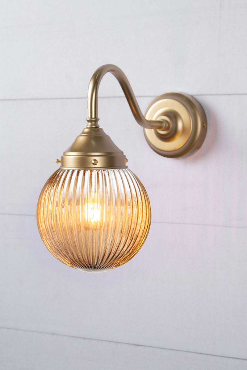 Exterior wall light with a gold/brass gooseneck arm and dark amber reeded shade.