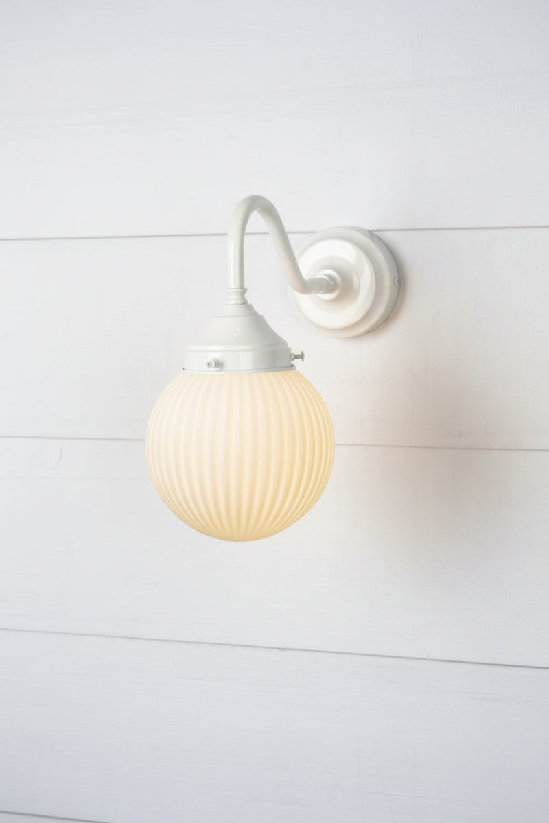 Opal glass ball shade with reeded detailing and an exterior gooseneck wall arm in white. 
