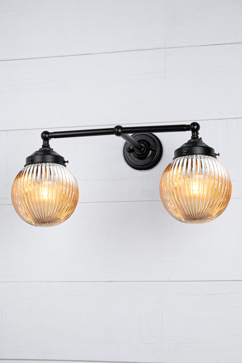 Black arm sconce with two dark amber reeded glass shades.