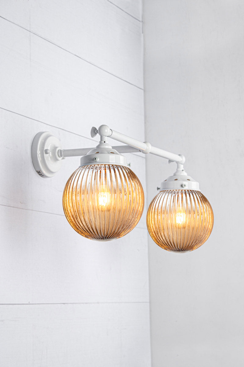 White double arm sconce with two dark amber reeded glass shades.