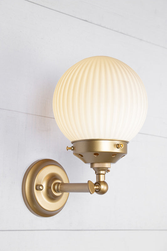 Opal glass reeded ball shade on a short gold/brass swivel straight arm.