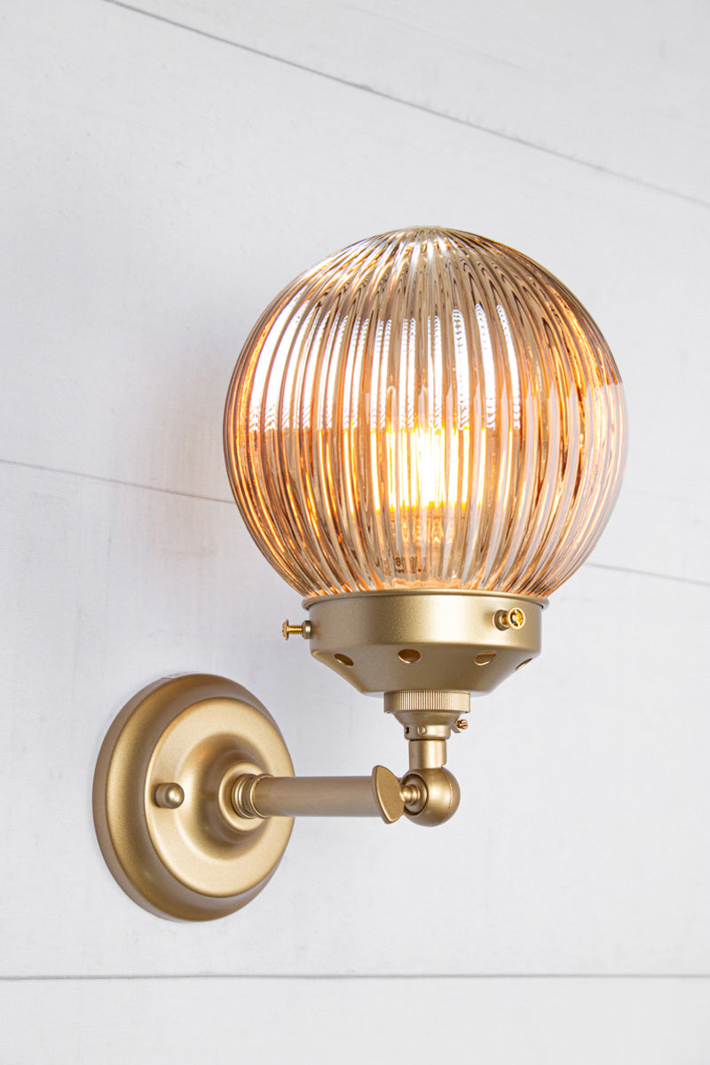 Dark amber glass reeded ball shade on a short gold/brass swivel straight arm.