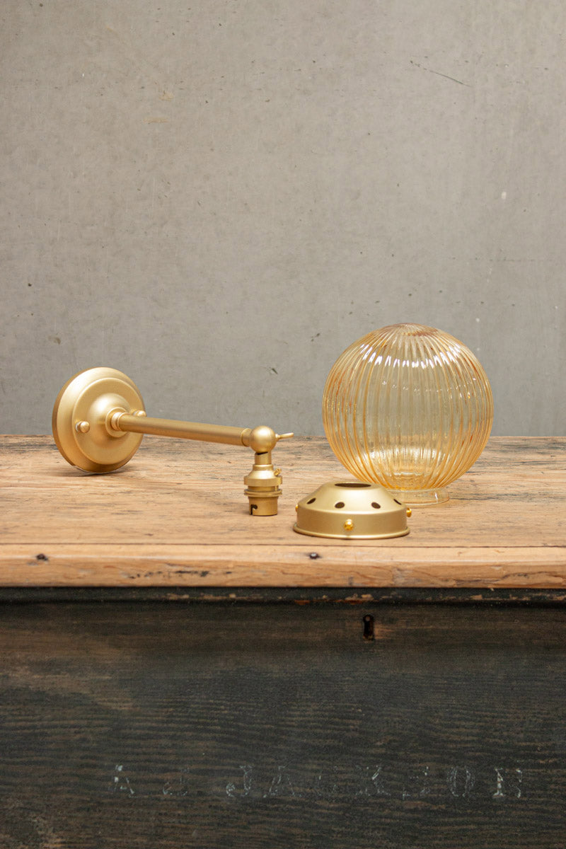 Disassembled Amber reeded glass ball light with gold/brass gallery and long straight arm. 