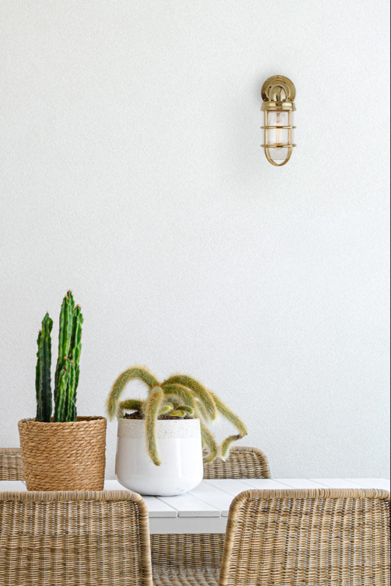 Polished brass outdoor wall light in a modern, clean outdoor area.
