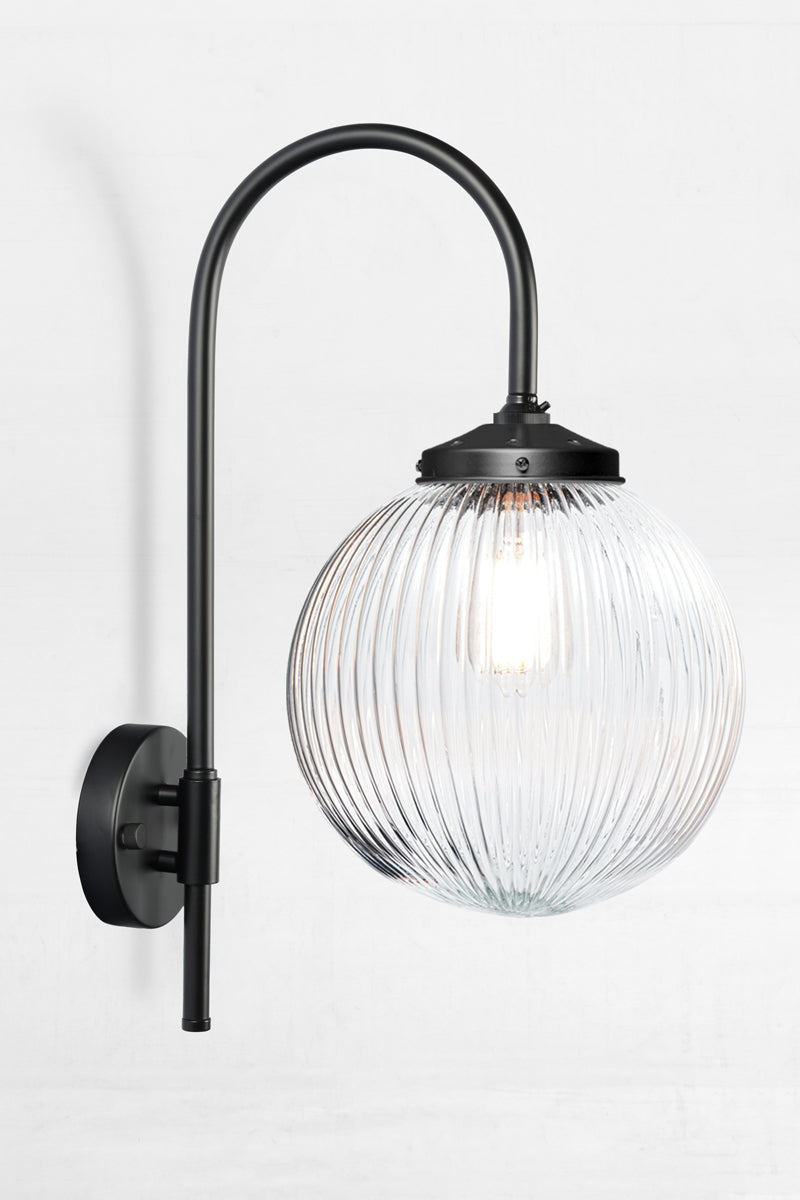 Shepard gooseneck wall light in black with a medium, clear, reeded glass ball shade. 