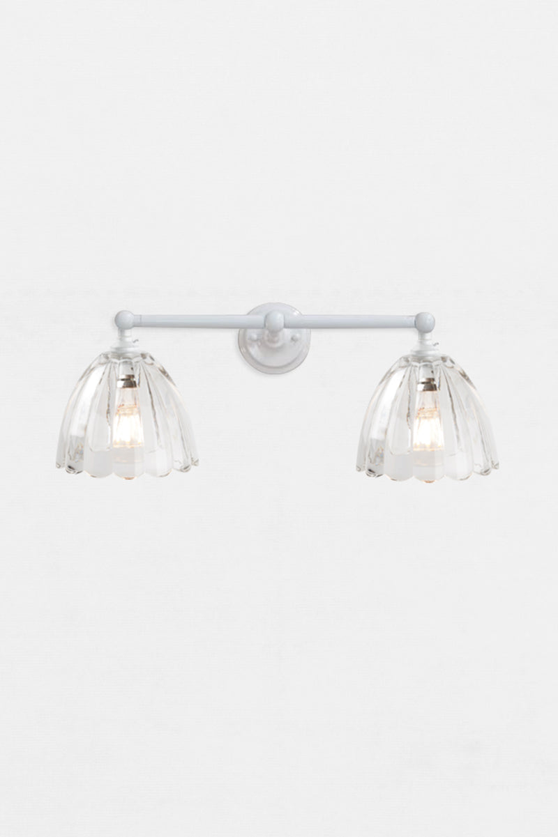Front view of the white double swivel wall sconce fixture with the two clear scalloped edge glass shades. 
