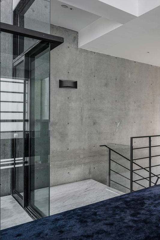 A black up/down wall lights at the top of stairs in a modern house. 