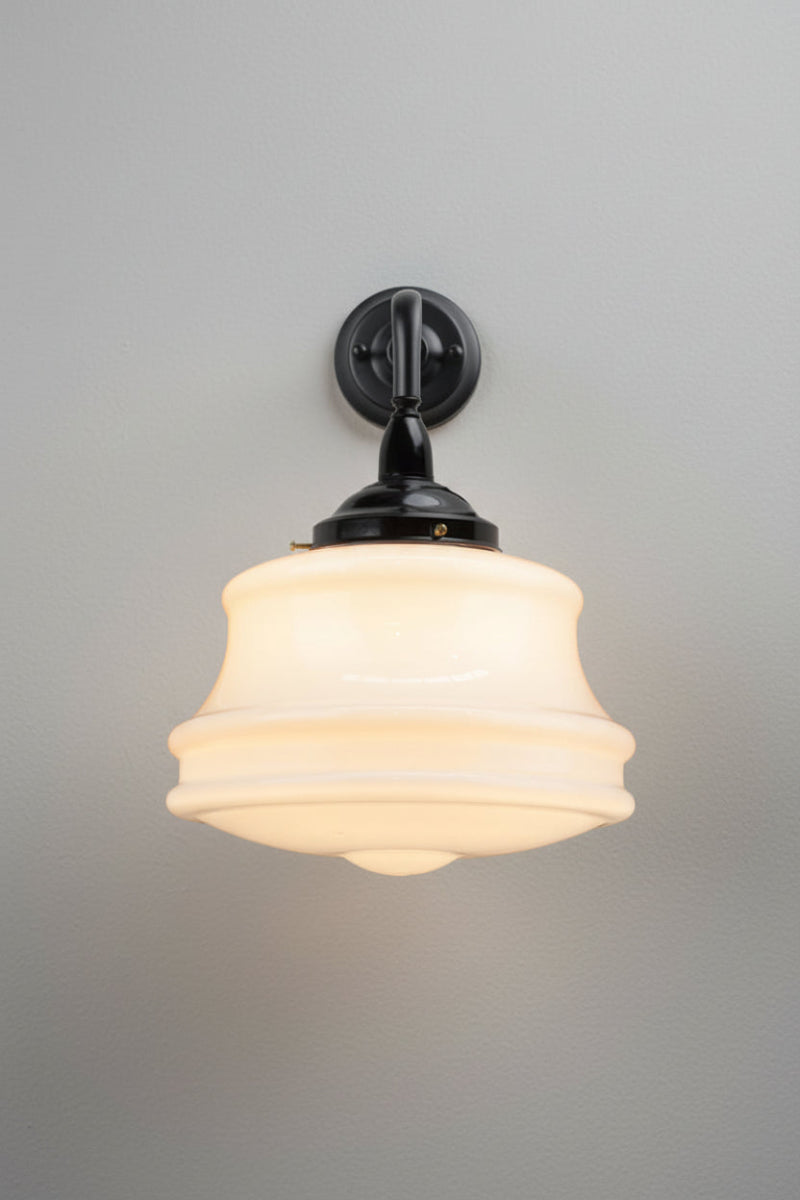Front view of the large opal glass schoolhouse style shade on a black steel 90 degree wall sconce. 