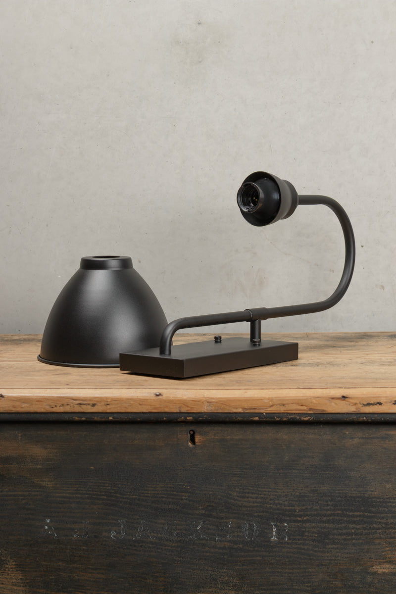 Uninstalled black wall light with goodsneck arm and dome shade. 