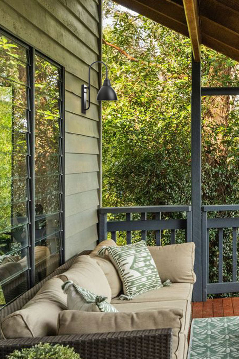 Gooseneck outdoor wall light on a rustic porch area. 