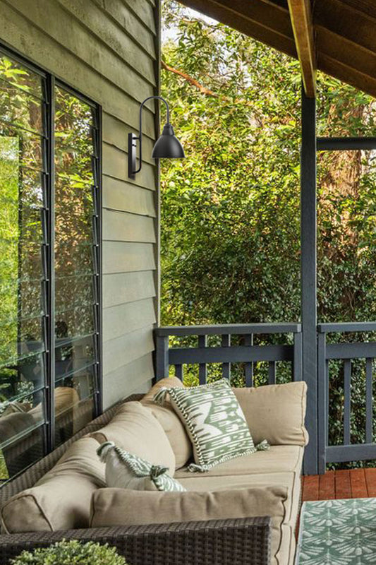 Gooseneck outdoor wall light on a rustic porch area. 