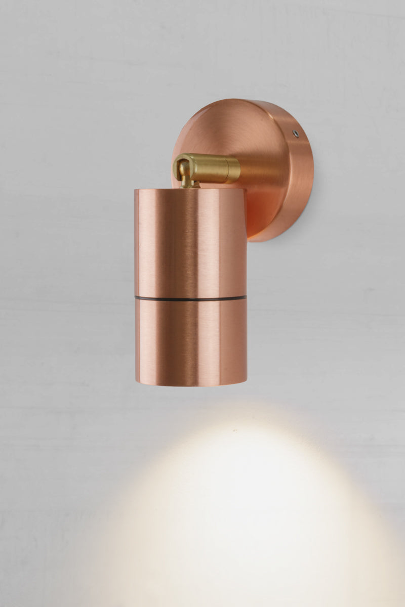 Polished copper outdoor spot light adjusted to face down.