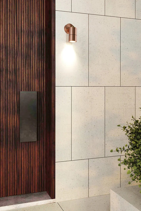 Polished copped adjustable spotlight next to a modern timber front door. 