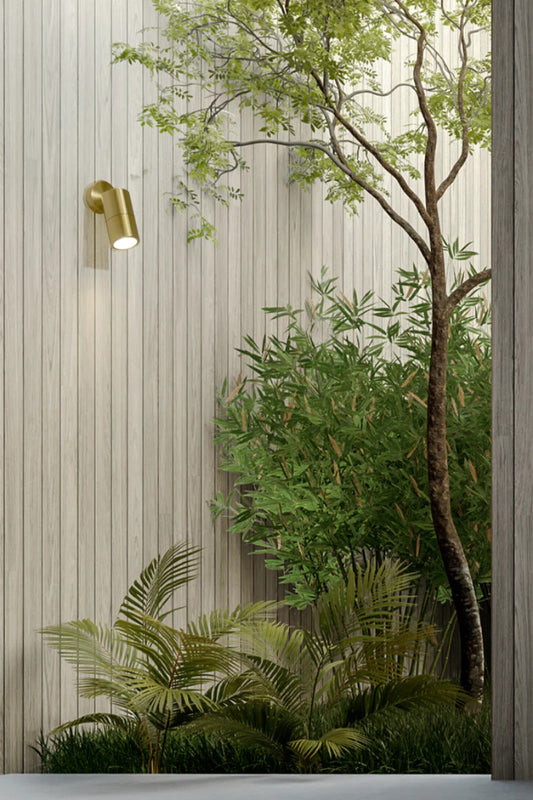 Polished Brass adjustable spotlight over a garden space. 