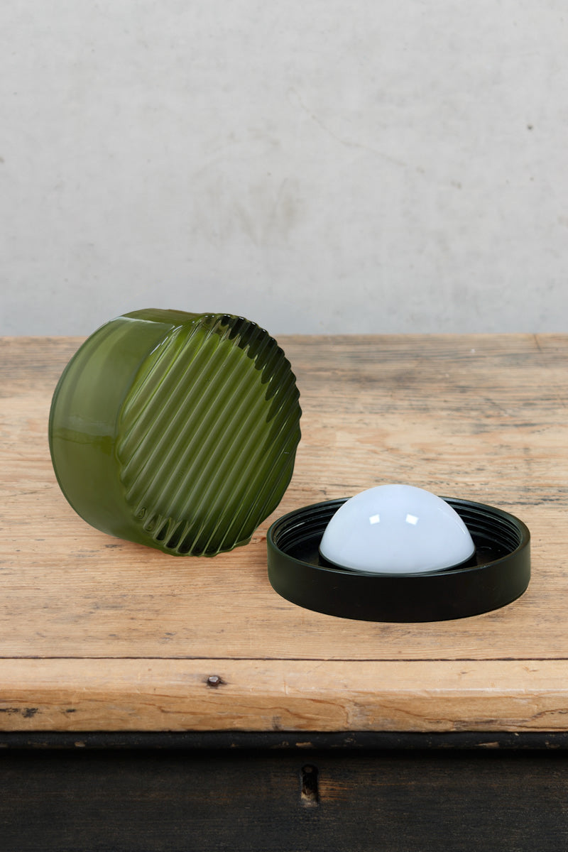 Green ribbed LED wall lights displayed in a styled setting with one illuminated and one turned off.