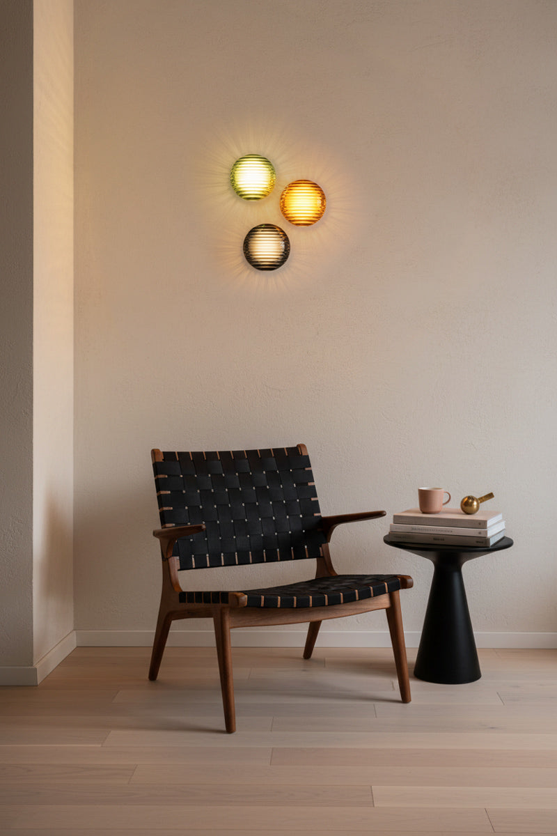 Modern chair with a small table and Bundle A: 3 x solid glass LED lights in three finishes as a wall feature above a reading nook. 