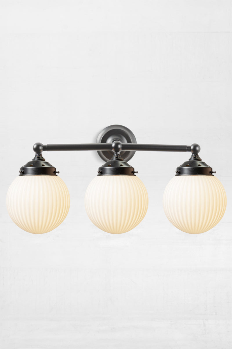 Triple straight arm wall sconce in black woth opal reeded glass ball shades- front view. 