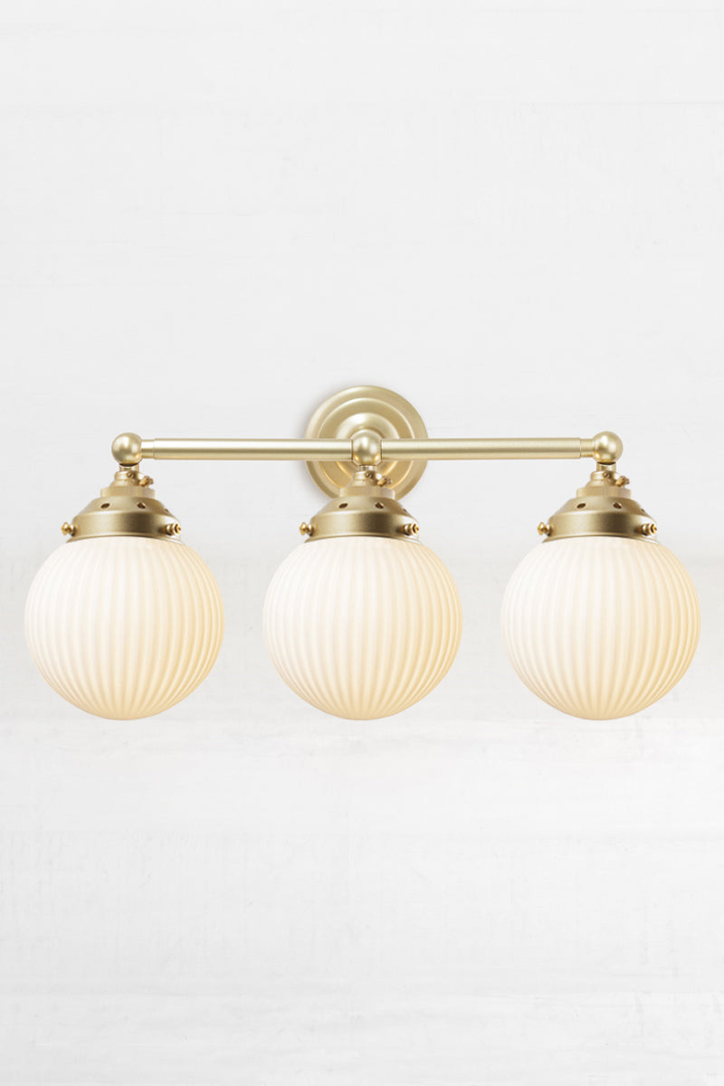 Gold/Brass three lampholder wall sconce paired with three opal reeded glass ball shades. 