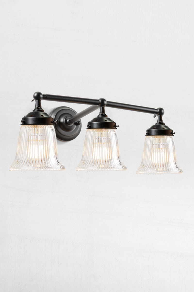 Black wall sonce with three clear reeded glass shades. 