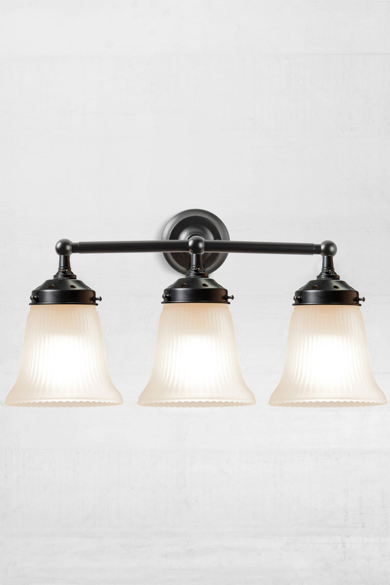 Front facing view of the triple black wall sonce with opal reeded glass shades. 