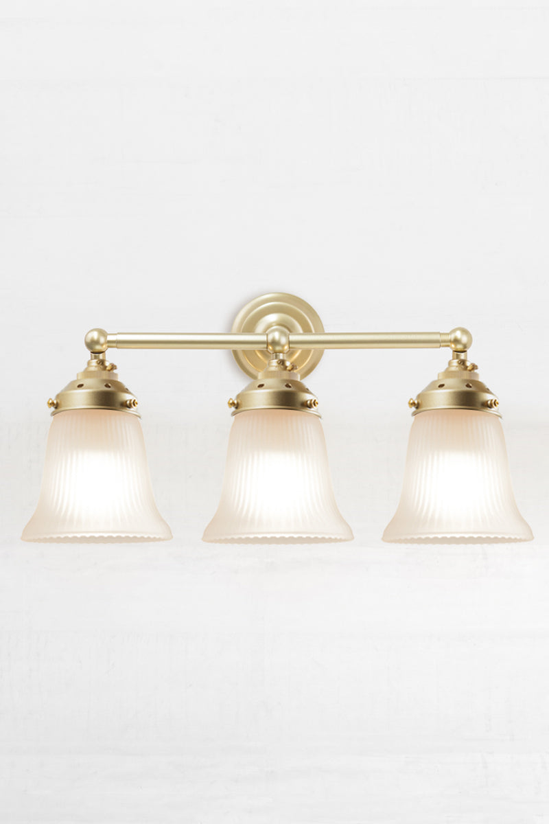 Front facing triple gold/brass wall sonce with opal reeded glass shades. 