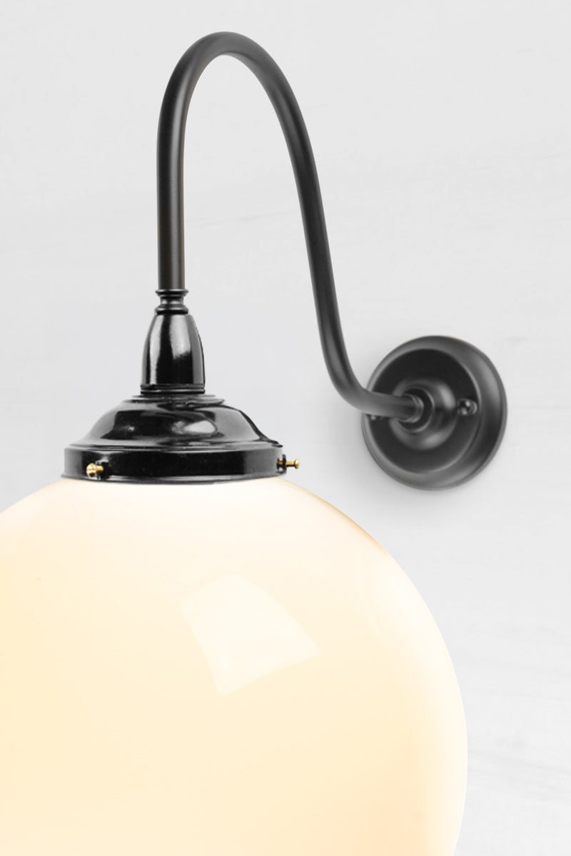 Close up of the extra large gooseneck wall sconce in black with a large opal glass ball shade. 