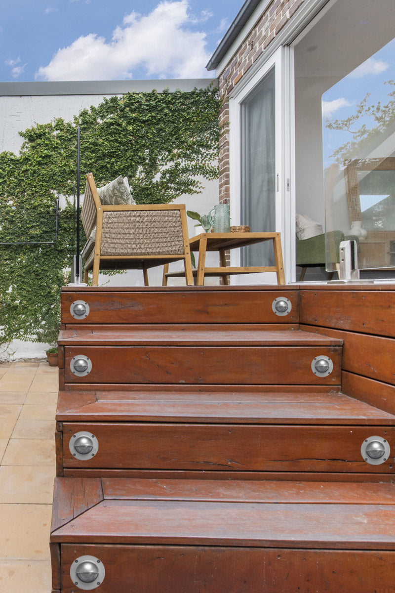 Silver step lights on timber steps up to a deck area. 